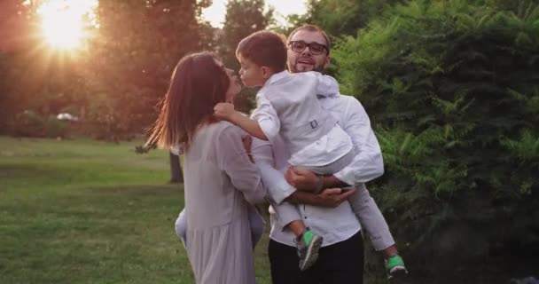 Güzel bir aile, iki çocuk ve genç ebeveynler yeşil parkın ortasında kameranın önünde harika vakit geçiriyorlar. — Stok video