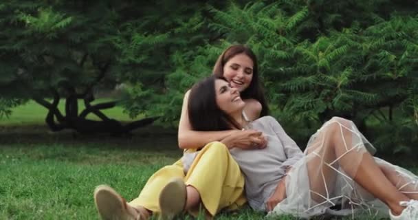 Yaz günü iki güzel bayan çimenlerin üzerinde birlikte eğleniyor gülümsüyor ve mutlu hissediyorlar. — Stok video