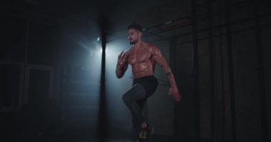 Kaslı ve terli müthiş güçlü bir vücut adamı çok sıkı çapraz egzersizler yapıyor. Spor salonunda konsantre oluyor.