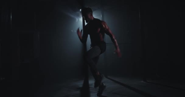 在一个黑暗的体育馆里，一个运动员在镜头前剧烈地操练 — 图库视频影像