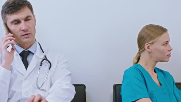 Charismatische Ärzte haben eine Pause in ihrem Zimmer, in dem sie mit einem von ihnen telefonieren oder sich mit einem digitalen Tablet Notizen machen. — Stockvideo