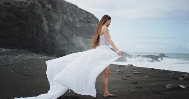 Menina bonita no vestido branco romântico olhando ao lado do litoral, ela aproveitando o tempo no meio da natureza — Vídeo de Stock