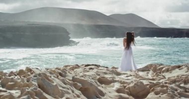 Beyaz elbiseli güzel manzaralı bayanın ortasında güzel vakit geçirirken denize bir göz atın. Harika bir yerde temiz havanın tadını çıkarıyor.