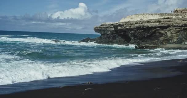 Перед камерой приморский пейзаж с черным песком пляжа и удивительный вид на скалы — стоковое видео