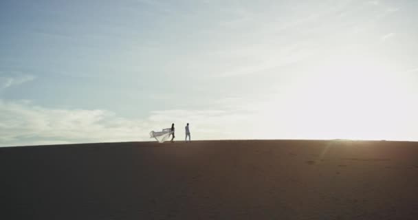 Beautiful couple walking through the large beach they walking through the sand lady have a amazing long dress — Stock Video
