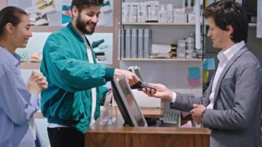 Ayakkabı dükkanında mutlu bir çift alışveriş yapan bir adama kredi kartını aldırır ve ayakkabıları karizmatik bir şekilde sattırır.