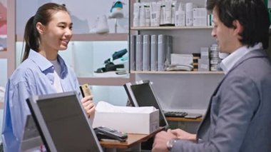 Ayakkabı dükkanındaki güzel Asyalı kadın yeni ayakkabılar aldı. Kredi kartını işlemlerini bitirmek için terminali kullanan satıcısına verdi. ARRI Alexa Mini 'de çekilen