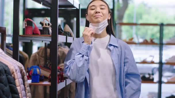 Glückliche Verkäuferin Porträt blickt direkt in die Kamera nehmen Sie die Schutzmaske ab und lächelt groß glücklich über das Ende der Pandemie in einem Schuhgeschäft Covid-19 — Stockvideo