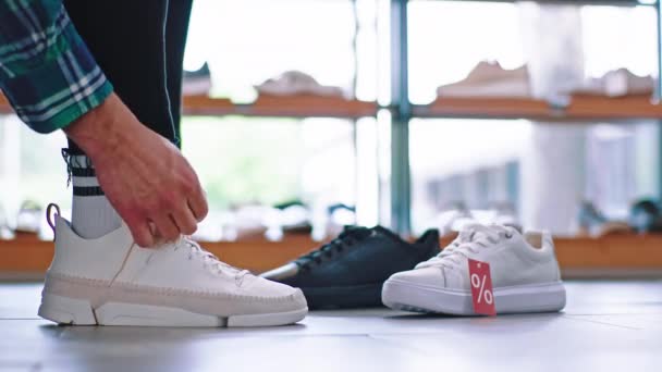 Details customer guy in a shoe shop take a sit on the sofa and wearing a new pair of sport shoes — Stock Video