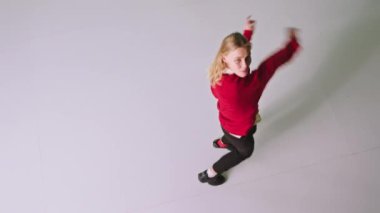 Kameranın önünde dans eden kırmızı kazaklı güzel bir bayan beyaz arka plandaki stüdyoda kameranın önünde eğleniyor.