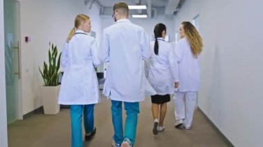 Geniş bir hastane koridorunda doktorlar ve hemşirelerden oluşan bir yürüyüş grubunda ve arkadan videolar çekerek hastaların bazı sorunlarını tartışıp sohbet ediyorlar.