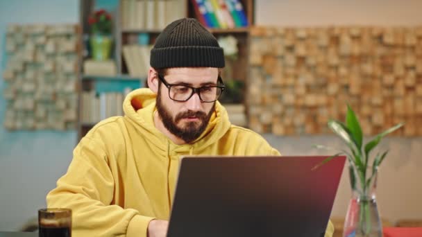 Отлично выглядящий парень в офисе, работающий над ноутбуком, пьющий кофе и печатающий что-то на ноутбуке — стоковое видео