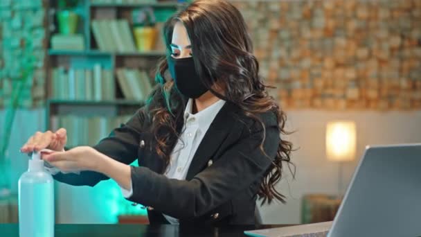 Hermosa mujer en la oficina con una máscara protectora en su cara tomar un poco de gel desinfectado y poner en todas las manos para protegerse del virus de un nuevo Covid-19 — Vídeo de stock
