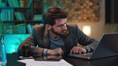 İş yerindeki ofis çalışanı biraz kestirir sonra uyanıp çok yorgun bir şekilde laptopuyla çalışmaya devam eder.