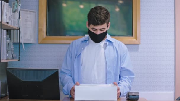Před kamerou mladý muž prodávající s ochrannou maskou dívající se přímo do kamery a sundat masku v karanténě nové Covid-19 — Stock video