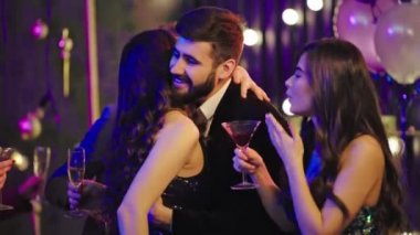 Doğum gününü kutlayan bir grup arkadaşın önünde parti atmosferi. Büyük bir gülümsemeyle birbirlerine sarılıyorlar ve akşamın tadını çıkarıyorlar. 4k.