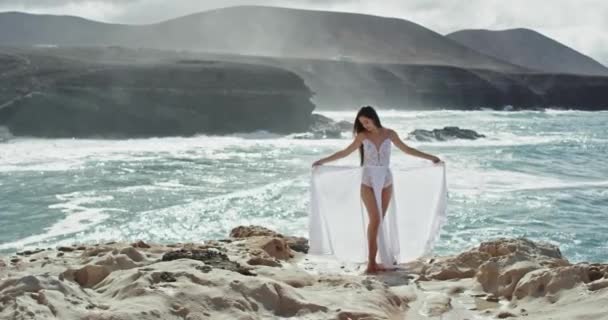 Bela natureza lugar com vista para a montanha e mar bela senhora em um vestido branco apreciando o momento, segurando seu vestido nas mãos — Vídeo de Stock