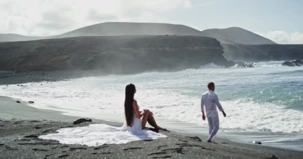 Pareja joven en el amor pasar tiempo juntos en la playa en frente de la playa que tienen un momento romántico juntos. 4k — Vídeos de Stock