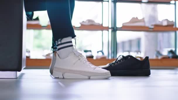Zbliżenie do gościa od aparatu spróbuj nową parę białych butów w sklepie obuwniczym, usiądź na kanapie. 4k — Wideo stockowe