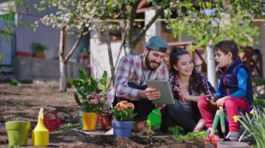 Bahçede eğlenirken, anne ve baba çocuklarıyla eğlenirken tablete koydukları bitkileri yerleştirirken doğru ekme talimatlarını görürler.