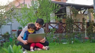 Babasıyla evdeki çimlerin üzerinde eğlenirken dizüstü bilgisayarda oyun oynarken heyecanlanıp birlikte vakit geçiriyorlar.