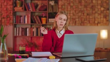 Kütüphanedeki bayan öğrencinin üniversite projesini bilgisayarını kullanarak yaptığını düşünüyor.