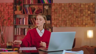 Modern ofis ortamında kahve içen bir kadın ve dizüstü bilgisayarın önünde çalışan bir kadın olarak bazı notlar yazıyor.