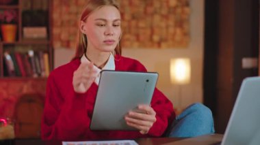 Çok çekici bir sarışın kadın evinde oturmuş elektronik tabletle online röportaj yapıyor.