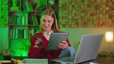 Bir şey almak için kredi kartı kullanan büyük, sarı saçlı, gülümseyen bir kadın. Elektronik tablet. Çok mutlu bir yüz ifadesi.