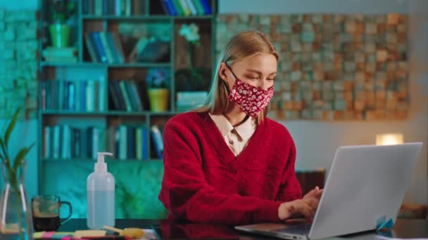 Conceito de mulher Covid-19 com uma máscara protetora trabalhando em seu escritório na frente do laptop ela digitando algo e usando algum papel para fazer algumas notas — Vídeo de Stock