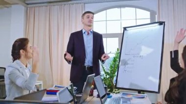 Konferans odası işadamı iş arkadaşlarıyla bir toplantı yapıyor. Yeni bir iş planını açıklıyorlar. İstatistikleri beyaz tahta kullanarak analiz ediyorlar.