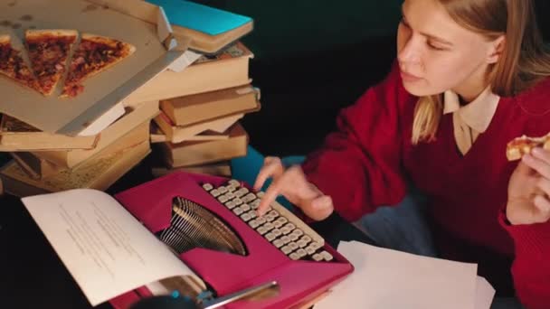 Подробиці дама в бібліотеці введіть якийсь проект коледжу на друкарській машинці одночасно їдять піцу — стокове відео