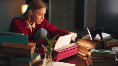 Çok karizmatik sarışın bayan kütüphanedeki daktiloya notlar yazmaya odaklanmış.