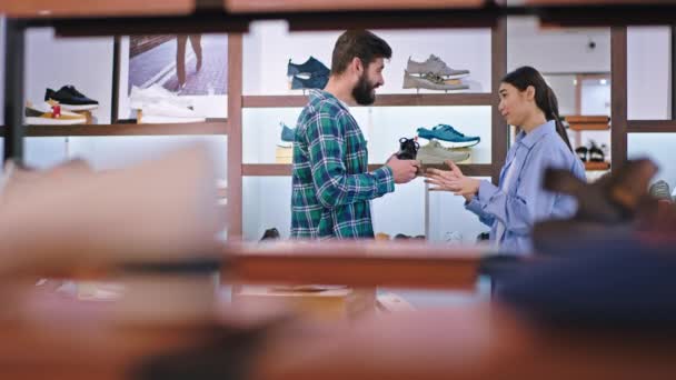 Heureux gars dans un magasin de chaussures ont une discussion avec sa petite amie dame asiatique regardant ils regardent les chaussures sorcière un à choisir — Video