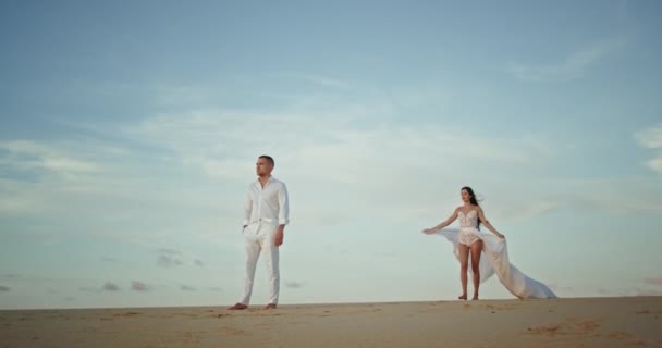 カリスマ的にいい見てカップルでビーチの女性に砂の中を歩く彼の男 — ストック動画
