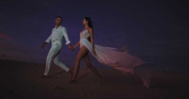 Dans le temps sombre dans le couple romantique côté plage se promener tout en serrant les mains de l'autre — Video