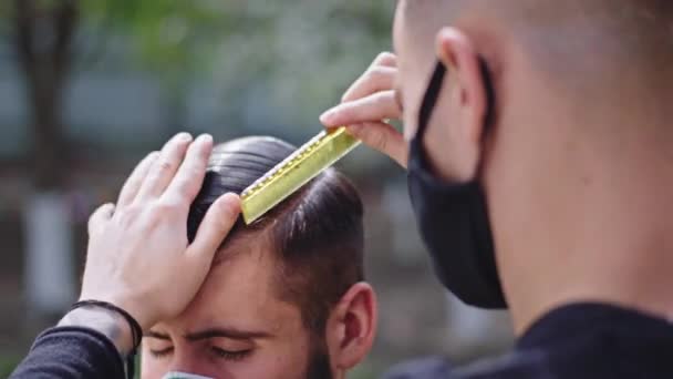 Goed uitziende jongens thuis in de tuin dicht bij de cameraman maken een professioneel kapsel ze dragen beschermende maskers pandemie 2019 Coronavirus. Neergeschoten op ARRI Alexa Mini — Stockvideo