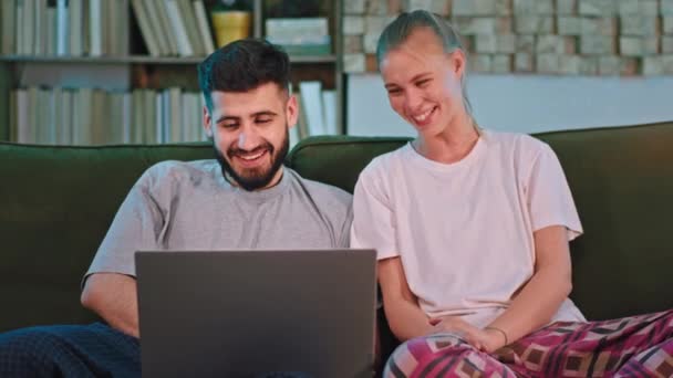 Casal muito animado em casa no sofá usando um laptop para ver sua família on-line conversando usando uma webcam laptop eles estão muito felizes — Vídeo de Stock