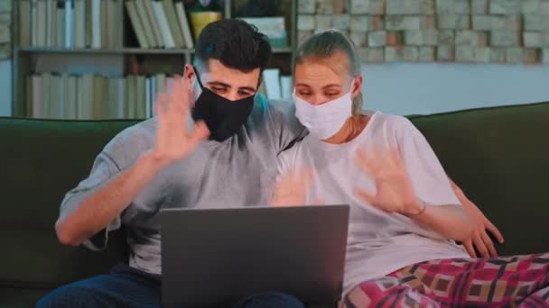 El uso de un ordenador portátil en la pandemia de la pareja con una máscara protectora de chat con su familia de la webcam que son muy felices. Disparo en ARRI Alexa Mini — Vídeo de stock