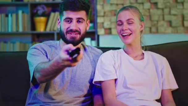 Feliz e sorrindo casal em casa assistindo tv na frente da câmera eles discutem sobre algum filme e aproveitando o tempo — Vídeo de Stock