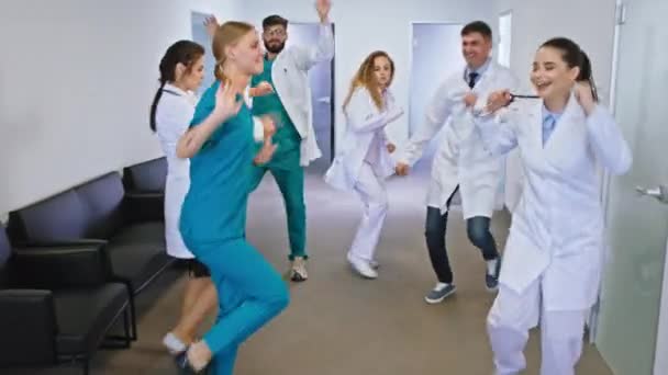 Corredor hospitalar moderno material hospitalar de médicos e enfermeiros dançando animado na frente da câmera — Vídeo de Stock