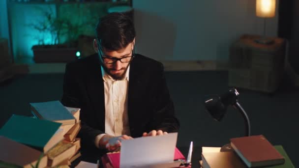 Красивый мужчина в очках работает онлайн из дома он печатает сконцентрированные некоторые документы. 4k — стоковое видео
