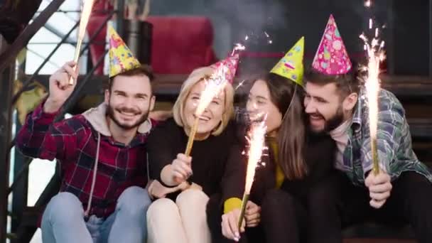 Desfrutando do grupo de aniversário de vários amigos étnicos em um apartamento moderno loft eles usam um brilho para fazer mais magia a noite — Vídeo de Stock