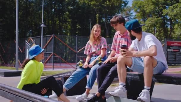 Glücklich und mit einer gut gelaunten Gruppe charismatischer Freunde mit coolen Outfits im modernen Skatepark nach einer Skatepause — Stockvideo