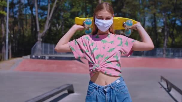 Mulher bonita no parque de skate urbano tirar sua máscara protetora e sorrindo bonito na frente da câmera ela segurando seu conceito de skate amarelo de COVID-19. Tiro em ARRI Alexa Mini — Vídeo de Stock