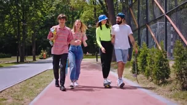 Dos carismáticos pareja multiétnica disfrutando del tiempo juntos mientras que tienen un paseo en un monopatín en un moderno parque de skate tienen una gran sonrisa y buen humor — Vídeos de Stock