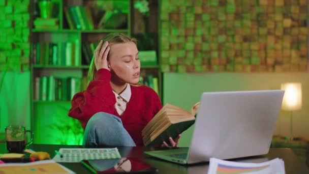 Улыбаясь, красивая леди читает книгу в библиотеке колледжа и наслаждается тем временем, которое она учится по книгам — стоковое видео
