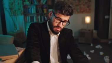 Karanlık ofisteki gözlüklü adam daktiloya kağıt yazdı sonra kağıdı aldı ve yere düştü.
