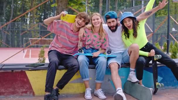 Zonnige dag in een modern skate park jonge groep vrienden multi-ethnic erg enthousiast voor de camera houden hun skateboard en genieten van de tijd voor de start om te rijden — Stockvideo