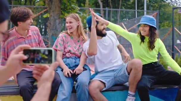 Asiática dama y su grupo de amigos con una gran sonrisa en un moderno parque de skate posando frente a un teléfono inteligente moderno algunos de los chicos tomar algunas fotos del grupo de amigos — Vídeo de stock